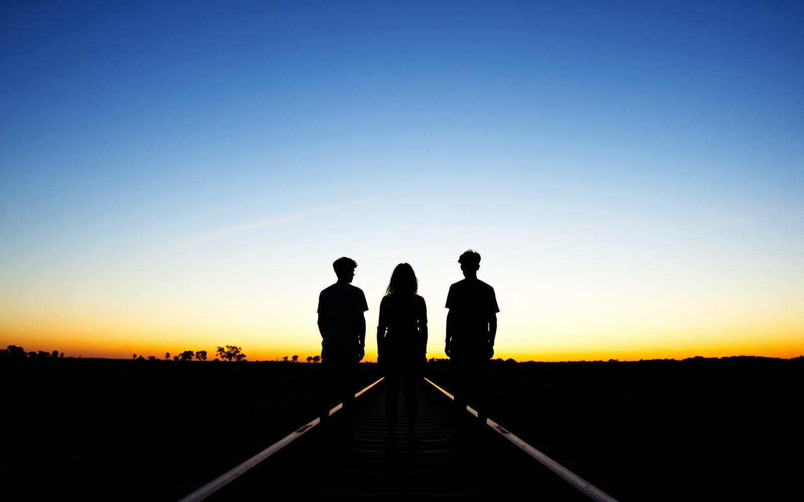 Three young friends on abandoned railway tracks at dusk